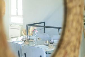 a dining room table with white chairs and a vase of flowers at Le Duplex de Bandol - Au centre in Bandol