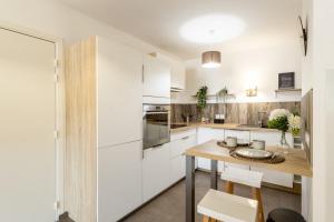 een keuken met witte kasten en een houten tafel bij La Terrasse de Duranne - Accès rapide TGV Aéroport in Aix-en-Provence