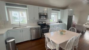 une cuisine avec des placards blancs et une table et des chaises blanches dans l'établissement Tickled Pink, à Harbour Island