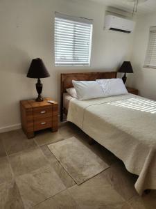 a bedroom with a bed and a night stand with a lamp at Tickled Pink in Harbour Island