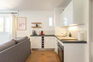 eine Küche mit weißen Schränken und einer Arbeitsplatte in der Unterkunft Magnifique T2 - Centre Sanary & Parking privé - Senaya in Sanary-sur-Mer