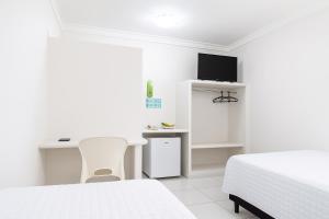 a bedroom with two beds and a desk and a tv at Hotel Absolar in Alagoinhas