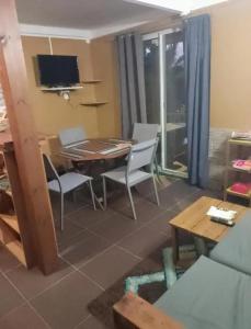 a living room with a table and chairs and a television at Appartement avec Terrasse à Capesterre-Belle-Eau in Petites Mamelles