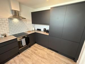 eine große Küche mit schwarzen Schränken und einem Herd in der Unterkunft Penthouse 2 bed 1 bathroom property in centre in Abingdon