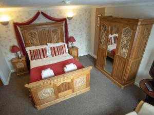a bedroom with a large wooden bed and a mirror at The Heath Inn in Leighton Buzzard +21 photos