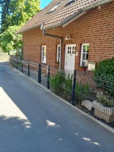 a brick house with a fence next to a street at Ferienwohnung Landhaus Scholz in Bad Münder am Deister