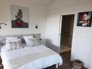 a bedroom with a white bed with white pillows at entre sel et mer in LʼÉpine