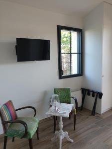 a living room with two chairs and a table and a tv at entre sel et mer in LʼÉpine