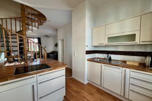 a kitchen with white cabinets and a staircase at Maisonette-Apartment für bis zu 6 Personen - Parkplatz - WLAN - Kingsize in Berlin