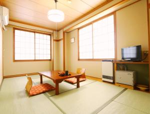 a living room with a table and two chairs and a tv at Kawatatsu in Nozawa Onsen