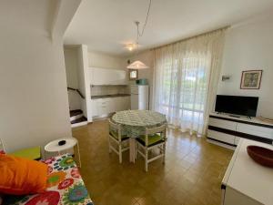 Una sala de estar con una mesa de comedor y una cocina. en Holiday home with garden and shared pool, en Porto Santa Margherita