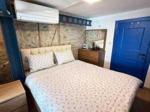 a bedroom with a bed with a blue door at Loft Cosy Stone House in Konak