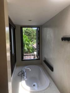 a bathroom with a bath tub with a window at Sea top room in Amphoe Koh Samui