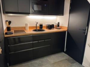 eine Küche mit schwarzen Schränken und einer Arbeitsplatte in der Unterkunft Chalet La Landonne chaleureux pour 2 in La Combe