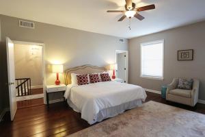 una camera con letto, ventilatore a soffitto e sedia di Oglethorpe Manor Main House a Savannah
