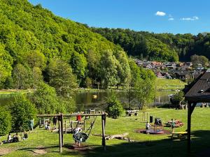 a park with a swing set and people in the grass at Ferienhaus Schieferterrasse - Waldsee Rieden - in Rieden