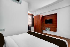 a hotel room with a bed and a tv at Super Townhouse Whitefield Railway Station Formerly Kadugudi Whitefield in Bangalore
