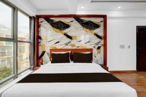 a bedroom with a large bed in front of a wall at Super Townhouse Whitefield Railway Station Formerly Kadugudi Whitefield in Bangalore +21 photos