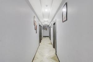 um corredor com paredes brancas e uma fileira de portas em Townhouse Central Prayagraj Bus Terminal Formerly Amba Palace em Civil Lines