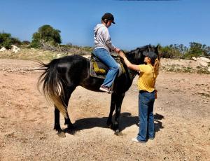 a woman is helping a man ride a black horse at Eco-Ranch Salomé in Sidi Kaouki