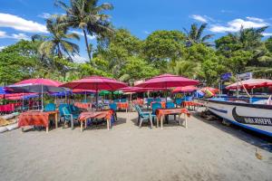 アランボールにあるHotel O Arambol Beach Formerly Hakuna Matataのビーチのパラソル付きテーブルと椅子