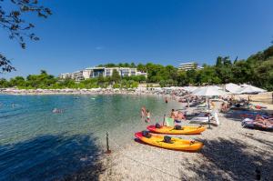 een groep mensen op een strand met boten in het water bij Apartments Biserka in Štanga