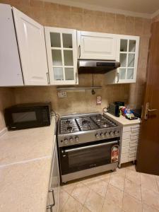 a kitchen with a stove and white cabinets at D3S 3BR Apartment in Makkah +24 photos