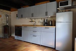 a kitchen with white cabinets and a white refrigerator at Ferienhaus Altes Elbschifferhaus in Königstein an der Elbe