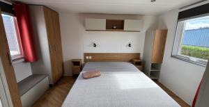 een kleine slaapkamer met een bed en twee ramen bij Mobil Home 40m2, Bonne Anse Siblu 4 étoiles in Les Mathes
