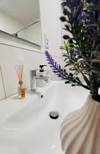 a bathroom sink with a vase with purple flowers in it at Zentrales, neumodernes Apartmentment Püttquartier No 3 in Ibbenbüren