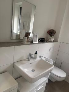a white bathroom with a sink and a toilet at Zentrales, neumodernes Apartmentment Püttquartier No 3 in Ibbenbüren +4 photos