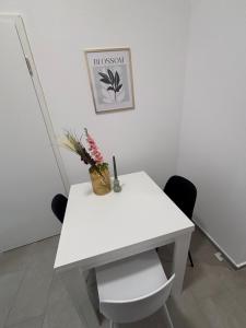 a white table with a vase of flowers on it at Zentrales, neumodernes Apartmentment Püttquartier No 3 in Ibbenbüren