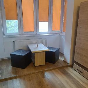 ein Tisch und zwei Hocker in einem Raum mit Fenstern in der Unterkunft Hunedoara Central Stay in Hunedoara