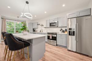 a kitchen with white cabinets and a stainless steel refrigerator at Spacious House with King Beds in Prime Location in Bloomfield +39 photos