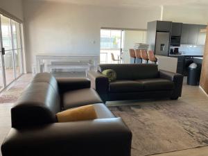 a living room with two couches and a kitchen at The Villa On Fontana in Yzerfontein