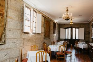 a restaurant with tables and chairs and a chandelier at Pazo Almuzara in Boborás