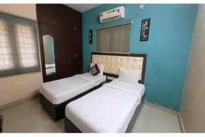 two beds in a room with blue walls at Via Blue Moon Residency in Chennai