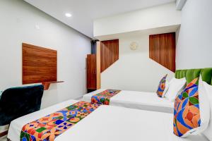 a hotel room with two beds and a chair at FabHotel Leon Square in Bengaluru