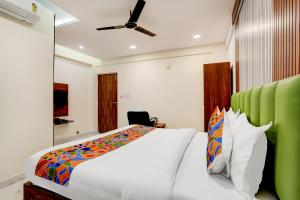 a bedroom with a white bed with a green headboard at FabHotel Leon Square in Bengaluru