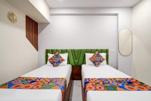 a room with two beds and a mirror at FabHotel Leon Square in Bengaluru
