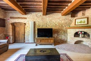 ein Wohnzimmer mit Fernseher und einer Ziegelwand in der Unterkunft 16th Century Townhouse, Large Garden Near Lake, Tuscany and Umbria - Sleeps 18 in Gioiella