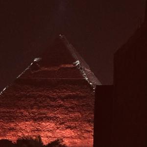 a tall building with red lights on it at night at The Pyramid Vault View INN in Cairo