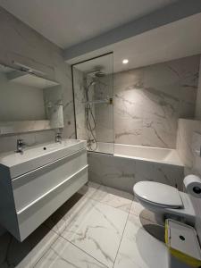 a bathroom with a tub and a toilet and a sink at Namur Suites in Mellet