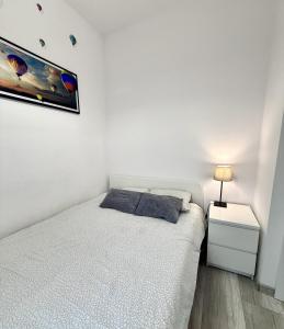 een witte slaapkamer met een bed en een nachtkastje bij theApartments Manufaktura in Łódź