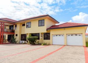 een huis met twee garagedeuren op een stenen oprit bij The Victory Residence in Accra