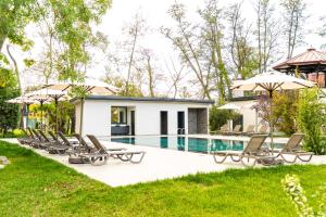 a pool with chairs and umbrellas next to a house at Wellwood Otel in Sapanca