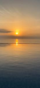 a sunset over the ocean with the reflection in the water at Bella view la perla in Moulay Bousselham +1 photo