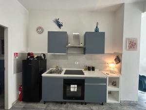 a kitchen with a sink and a black refrigerator at Seaside two-room apartment in Torvaianica