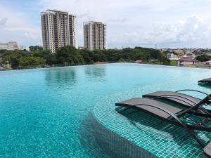a swimming pool with two lounge chairs in the water at Alor Setar Tower 3 Bedroom Suite Malay Only in Alor Setar