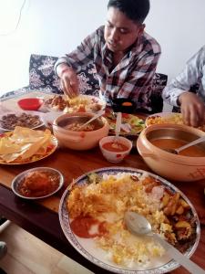 un hombre sentado en una mesa con un plato de comida en Hridhaan Hometay, en Kalimpong